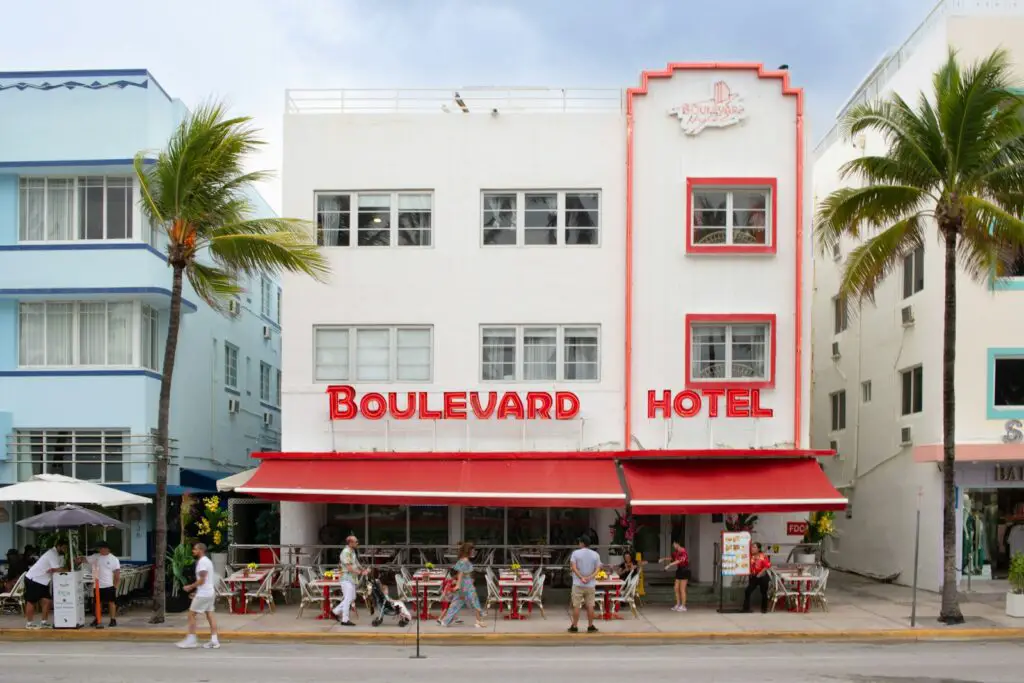 A red and white hotel with palm trees in front of it