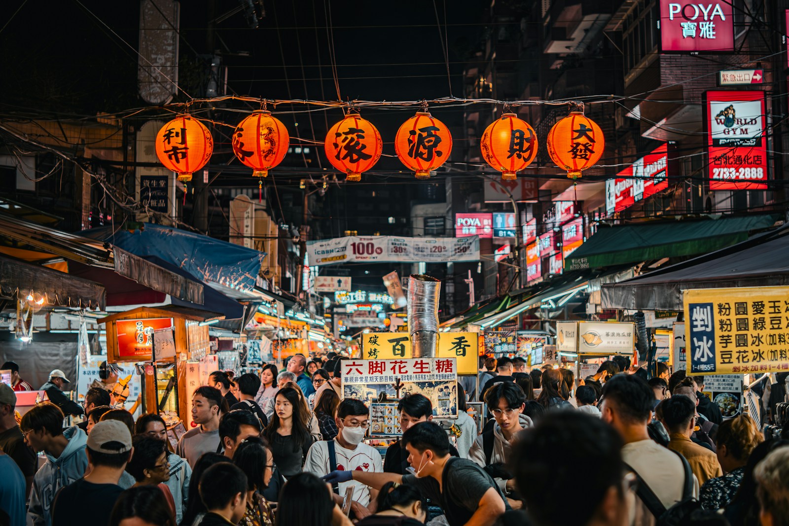 a crowd of people walking through a street at night