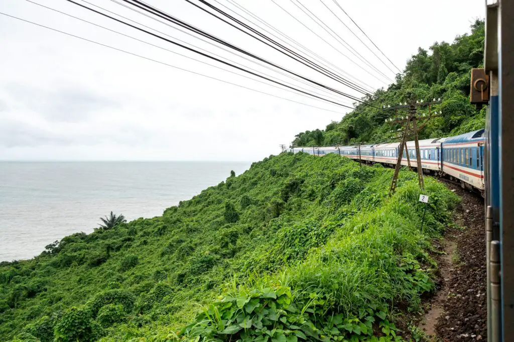 a train traveling down tracks next to a lush green hillside