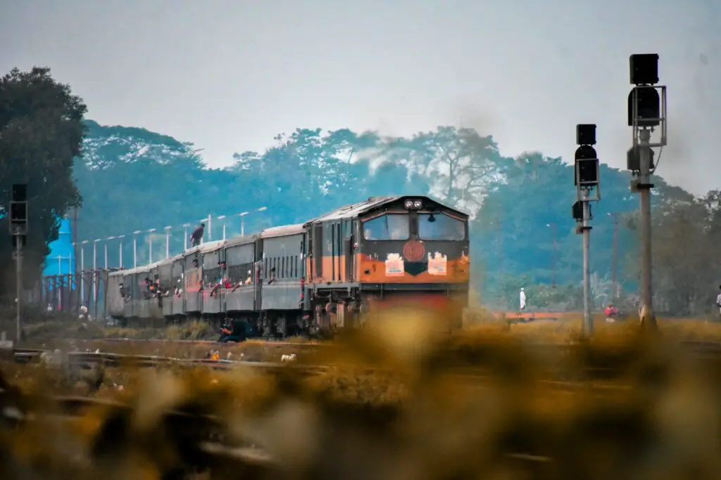 A train traveling down train tracks next to a forest