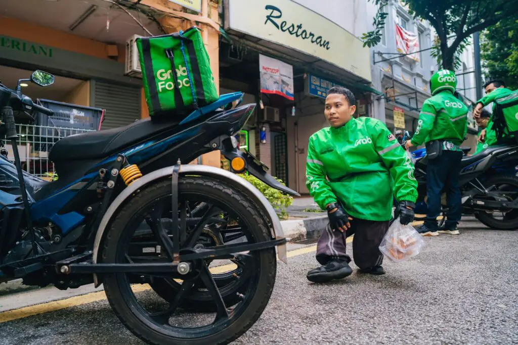 a man in a green jacket is standing next to a motorcycle