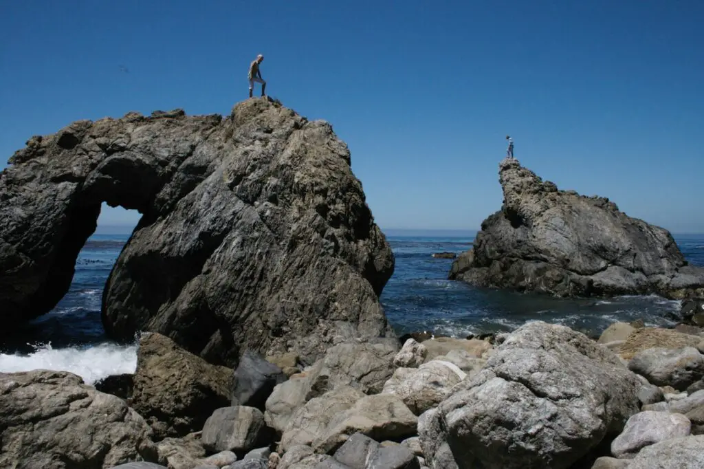 person standing on rock formation near sea during daytime