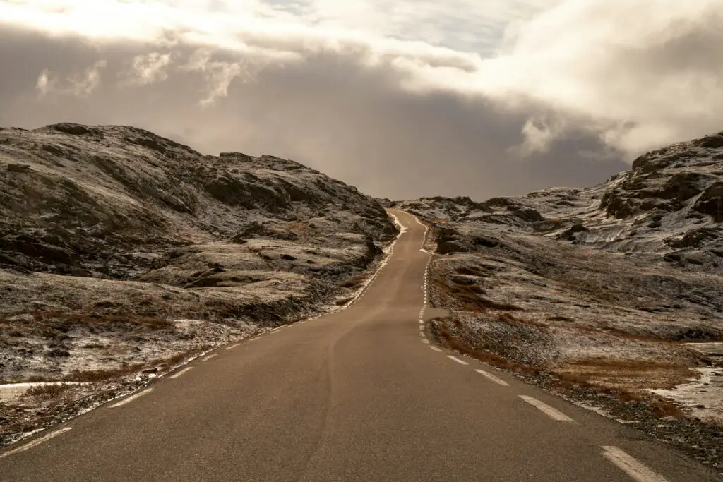 an empty road in the middle of a mountain range